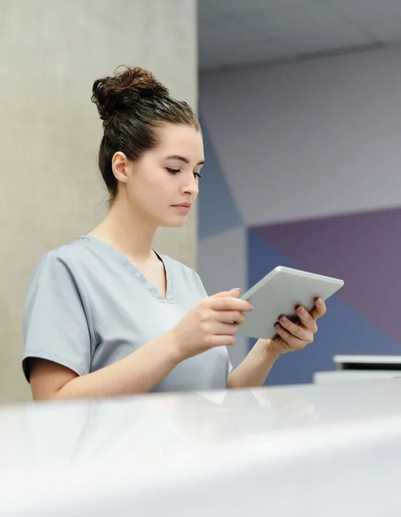 Secrétaire en blouse consultant l’agenda du cabinet sur une tablette